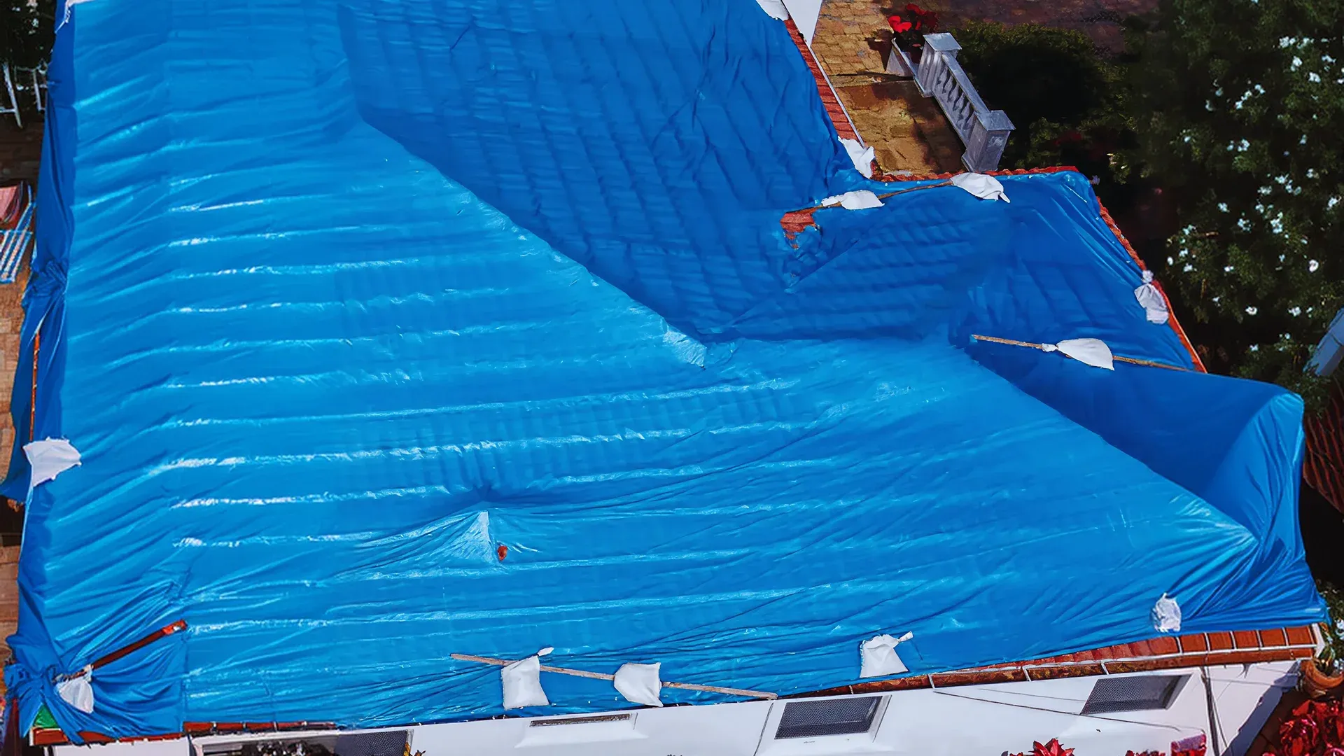 Temporary roof repair using a tarp on a damaged roof in Odessa